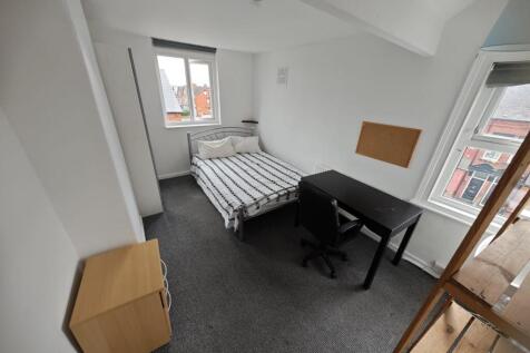 A neat single bedroom featuring a bed with stri...