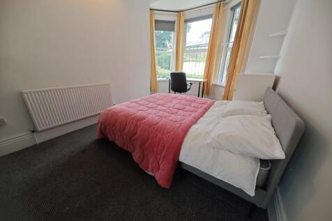 A bright double bedroom featuring a large windo...