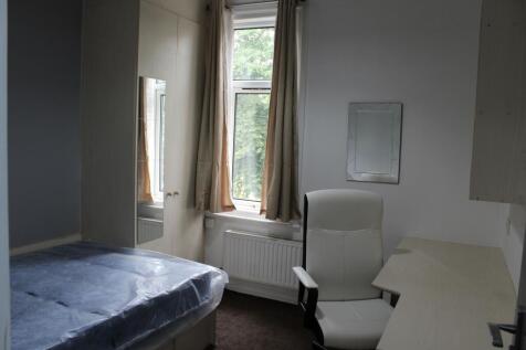 A tidy and functional small room with a bed, de...