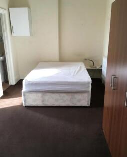 A spacious double bedroom with a bed and wardro...
