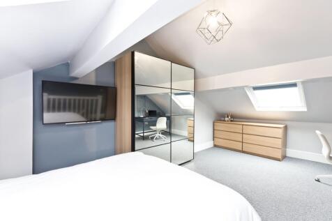A spacious, modern bedroom featuring a large be...