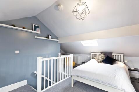 A bright, modern bedroom with a sloped ceiling,...