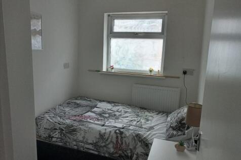 A cozy bedroom with a neatly made bed featuring...