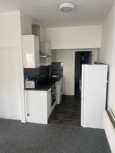 A compact, modern kitchen with white cabinetry,...