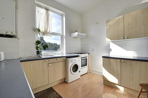 Bright and tidy kitchen featuring light wood ca...