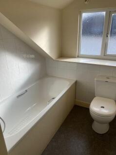 A clean and bright bathroom with a bathtub, whi...