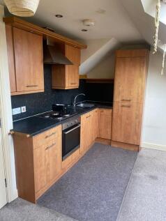 Modern compact kitchen with wooden cabinets, bl...