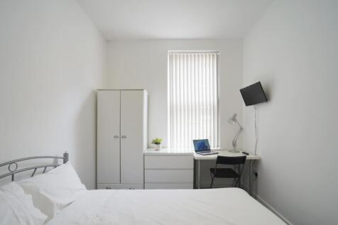 A bright and tidy bedroom featuring a comfortab...