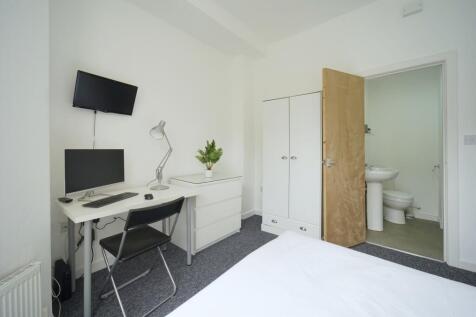 A bright and tidy bedroom featuring a workspace...