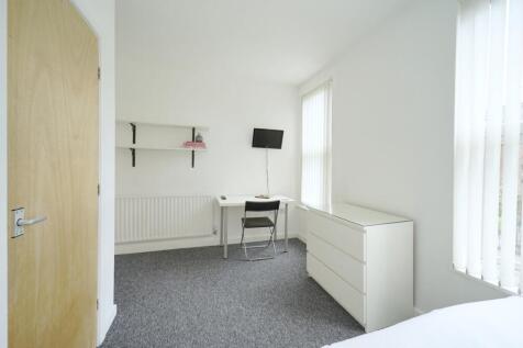 A tidy, well-lit student room with a desk, chai...