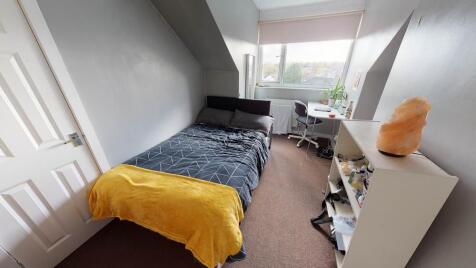 A cozy single bedroom featuring a neatly made b...