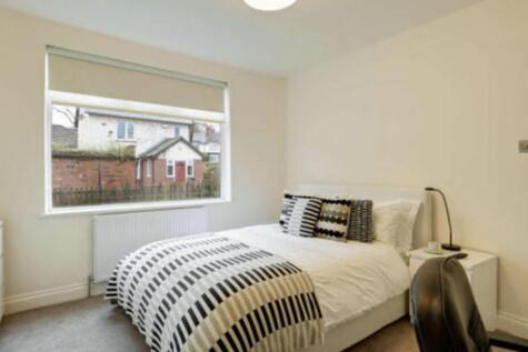 A well-lit, tidy bedroom featuring a comfortabl...