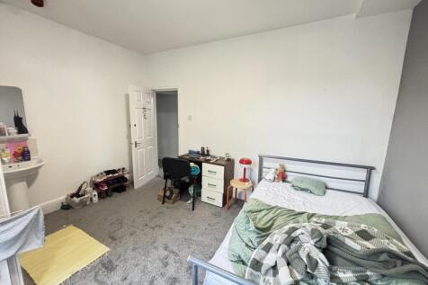 A cozy bedroom featuring a single bed, a desk, ...