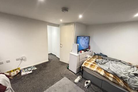 A modest bedroom with a single bed, a TV, and m...