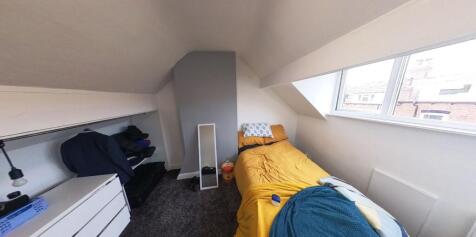 A cozy single bedroom featuring a comfortable b...