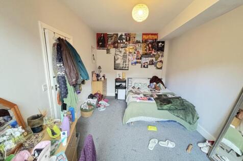 A cluttered bedroom with various items scattere...