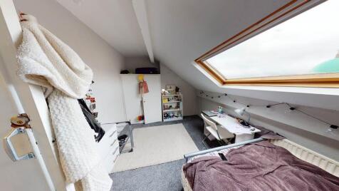A cozy and well-lit bedroom with a skylight win...