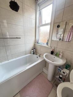 A bright and tidy bathroom featuring a bathtub,...
