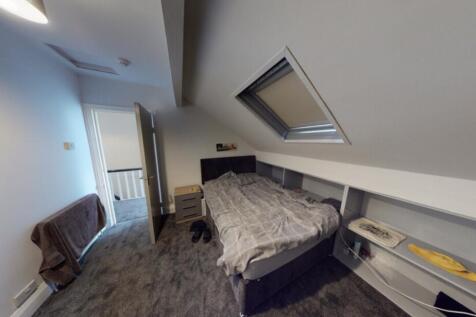 A spacious, well-lit bedroom with a double bed,...