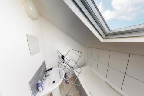 A clean and bright bathroom with a large skylig...