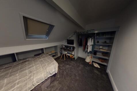 A cozy bedroom featuring a single bed, with som...