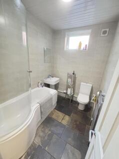 A clean and bright bathroom featuring a bathtub...