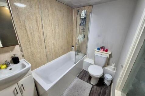 A bright and clean bathroom featuring a bathtub...