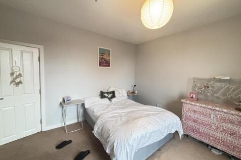 A cozy single bedroom featuring a neatly made b...