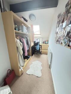 A cozy bedroom featuring an open wardrobe with ...