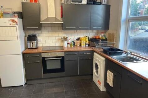 A modern kitchen featuring dark cabinetry, a co...