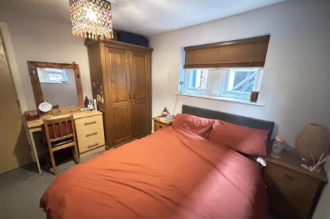 A cozy bedroom featuring a double bed with pink...