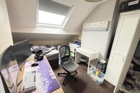 A cozy bedroom with a sloped ceiling and a wind...