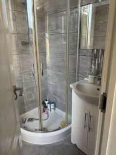 A modern, compact bathroom featuring a corner s...