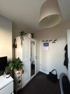 A cozy bedroom featuring a white wardrobe, a sm...