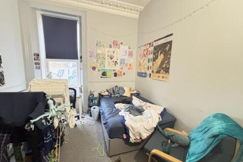 A cozy student bedroom with a bed, some study m...