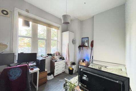 A modest bedroom with a window providing natura...