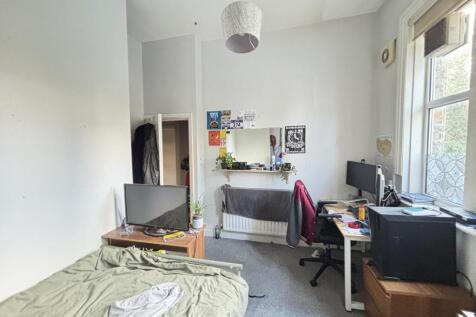 A cozy bedroom featuring a bed, desk, and windo...