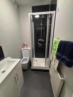 A modern, compact bathroom featuring a shower e...