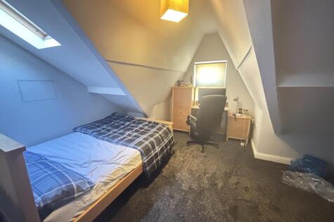 A cozy single bedroom with a neatly made bed, a...