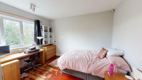 A cozy bedroom featuring a double bed with pink...