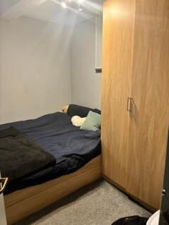 A cozy single bedroom featuring a neatly made b...