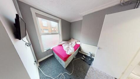 A cozy single bedroom featuring a bed with a br...