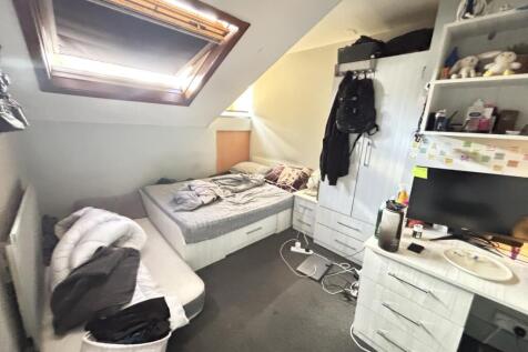 A cozy bedroom featuring a single bed, a desk, ...