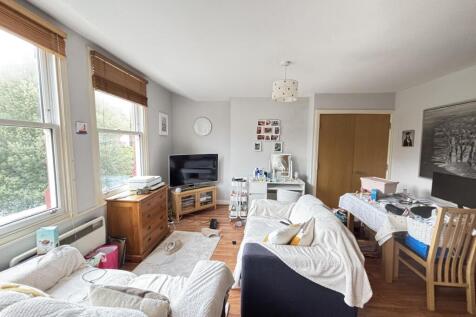 A spacious, bright living room filled with natu...