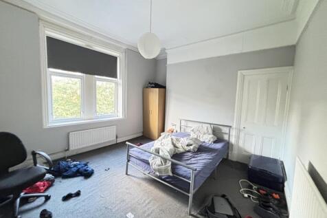 A modest bedroom featuring a single bed with a ...