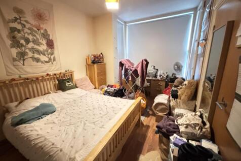 A cozy bedroom featuring a wooden bed frame, wi...