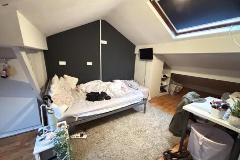 A cozy bedroom featuring a single bed with bedd...