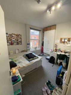 A well-lit, cozy student bedroom featuring a do...