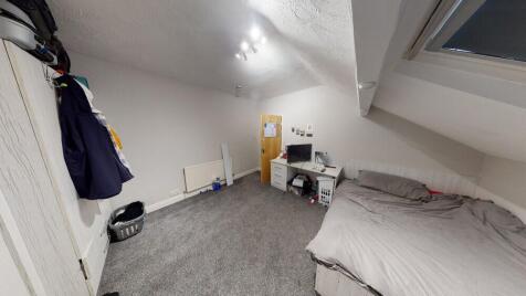 A cozy bedroom with a slanted ceiling and a win...