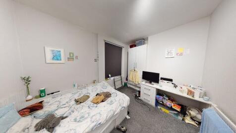 A modest bedroom with a double bed, cluttered w...